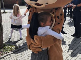 Dziewczynka przytula się do maskotki straży miejskiej Rysia