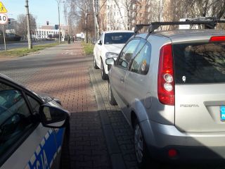 Radiowóz policyjny oraz nieprawidłowo zaparkowane samochody