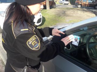 Strażniczka miejska podczas pozostawiania upomnienia kierującemu za niewłaściwe parkowanie
