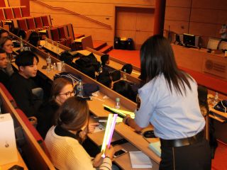 Strażniczka miejska przekazuje opaski odblaskowe studentom