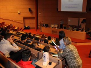 Strażniczka miejska i pracownik dydaktyczny uniwersytetu przekazują  opaski odblaskowe studentom