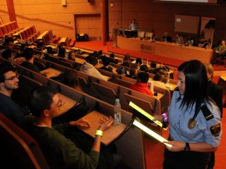 Strażniczka miejska przekazuje opaski odblaskowe studentom