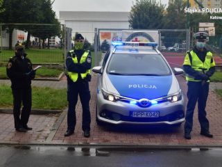 Strażniczka miejska oraz policjanci przy policyjnym radiowozie