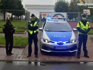Strażniczka miejska oraz policjanci przy policyjnym radiowozie