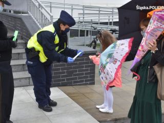 Policjantka i strażniczka miejska przekazują dziewczynce element odblaskowy