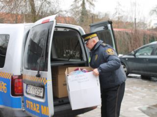 Strażnik miejski z darami dla bezdomnych zebranych przez uczniów Szkoły Podstawowej nr 64