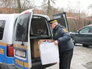 Strażnik miejski z darami dla bezdomnych zebranych przez uczniów Szkoły Podstawowej nr 64