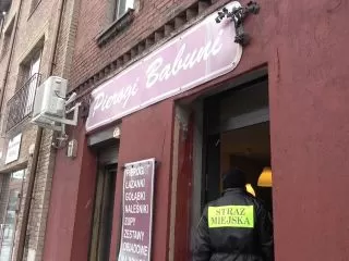 Strażnik miejski wchodzi do restauracji biorącej udział w pomocy bezdomnym