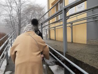 Strażniczka miejska pomaga seniorce podczas przejścia do punktu sczepień