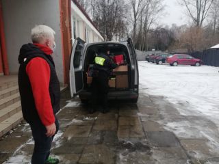 Strażniczka miejska oraz nauczyciel ze szkoły podczas załadunku odzieży do samochodu