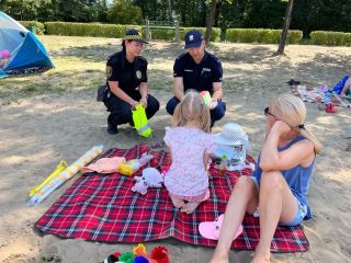 Strażniczka miejska i policjant podczas rozmowy z wypoczywającymi nad wodą