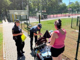 Strażniczka miejska i policjant wręczają upominek