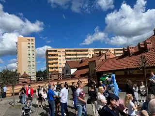 Rodzice, dzieci, mundurowi i maskotki przed szkołą