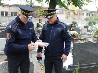 Strażnicy miejscy zapalają znicz